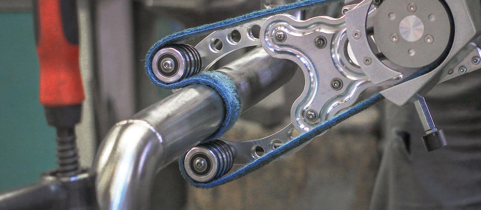 Bild på en person som satinslipar ett rostfritt rör