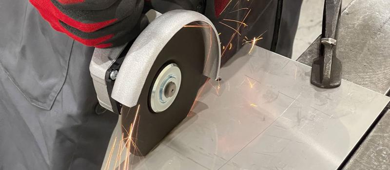 Bild på person som kapar en metallplåt med hjälp av en armerad kapskiva